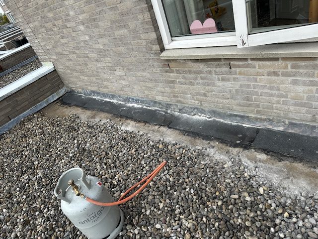 Muuraansluiting opnieuw ingebrand tegen het metselwerk van een plat dak